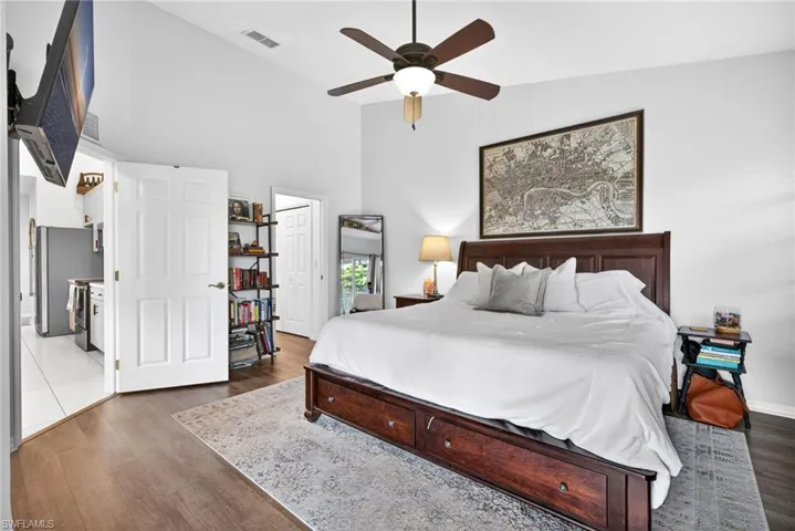 Primary Bedroom featuring vaulted ceilings, wood-finish flooring, and a ceiling fan with integrated lighting