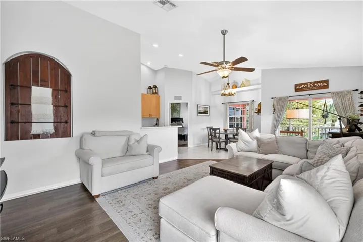 Spacious living area featuring vaulted ceilings, a ceiling fan with integrated lighting, and wood-finish flooring