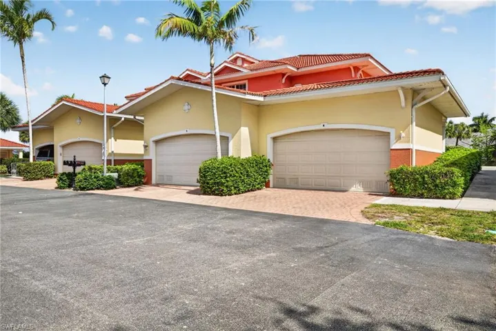 Exterior featuring a vibrant red tile roof, pale yellow stucco siding, and a two-car garage with a light beige door