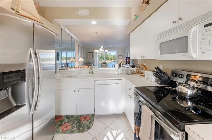 Kitchen with light tile patterned floors, a sink, stainless steel appliances, light countertops, and white cabinetry