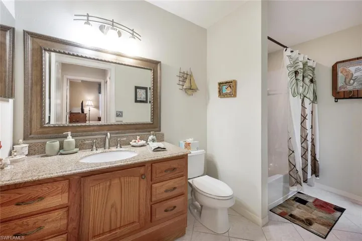 Bathroom featuring vanity, baseboards, tile patterned flooring, toilet, and shower / tub combo with curtain