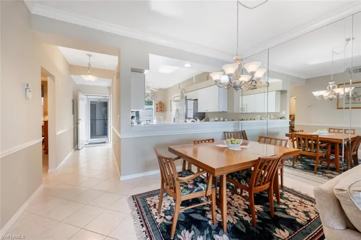 Dining area with ornamental molding, light tile patterned floors, baseboards, and a chandelier
