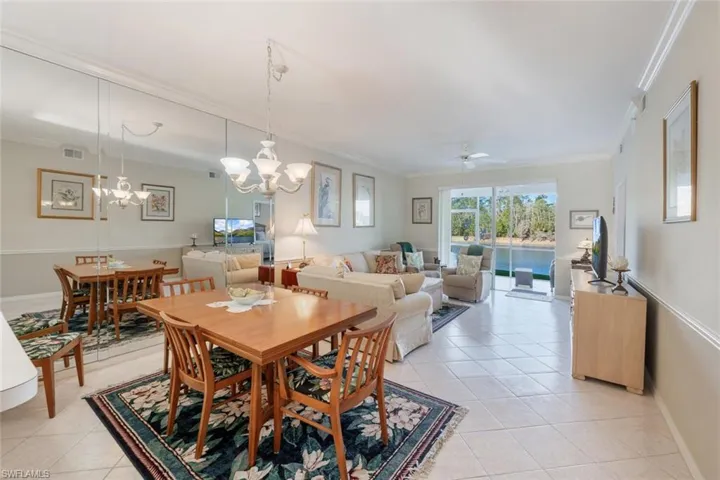 Dining area with visible vents, ornamental molding, ceiling fan with notable chandelier, light tile patterned floors, and baseboards