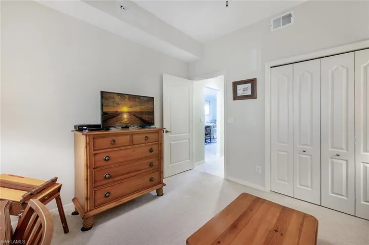 Bedroom with baseboards, visible vents, light carpet, and a closet