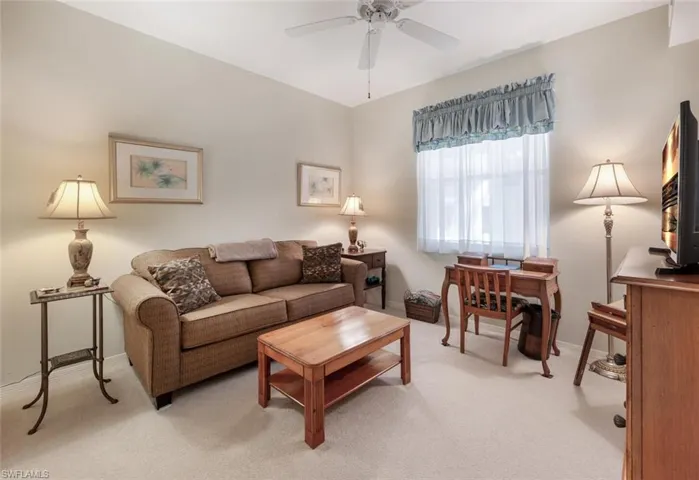 Living room featuring baseboards, light colored carpet, and ceiling fan