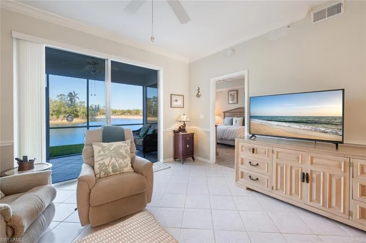 Living area with visible vents, crown molding, baseboards, light tile patterned floors, and a ceiling fan