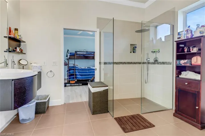 Bathroom featuring ornamental molding, a walk in shower, vanity, and tile patterned floors