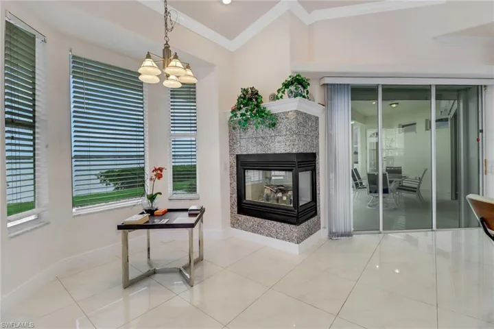 Hallway featuring a notable chandelier, baseboards, tile patterned flooring, and crown molding