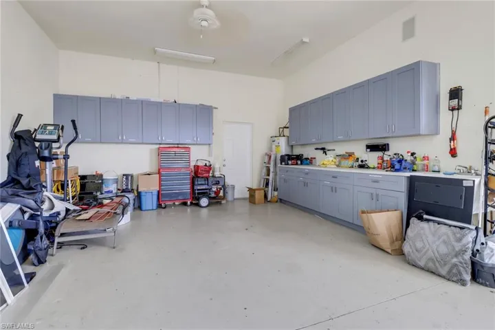 Garage featuring water heater, visible vents, and a workshop area