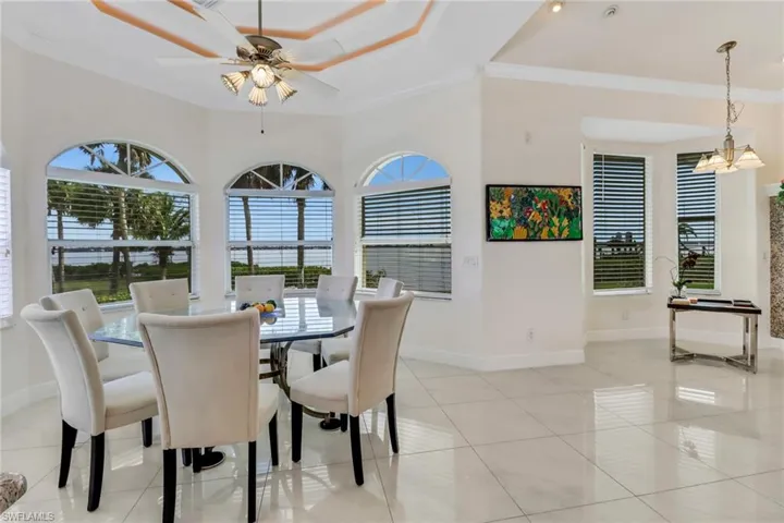 Dining space with light tile patterned floors, ornamental molding, a raised ceiling, and baseboards