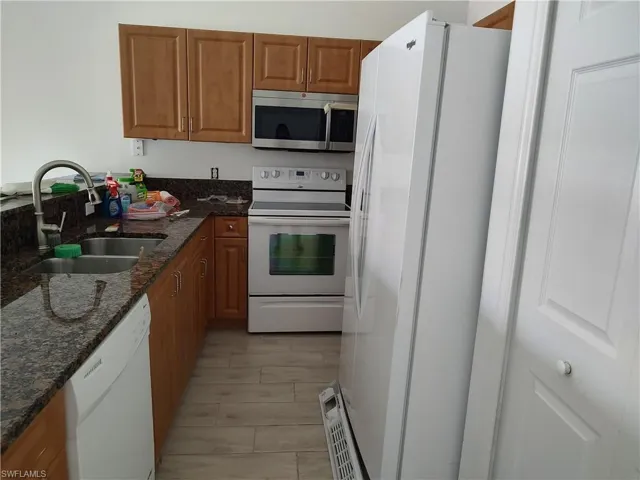 Kitchen with white appliances, granite counters, and wood finish cabinets