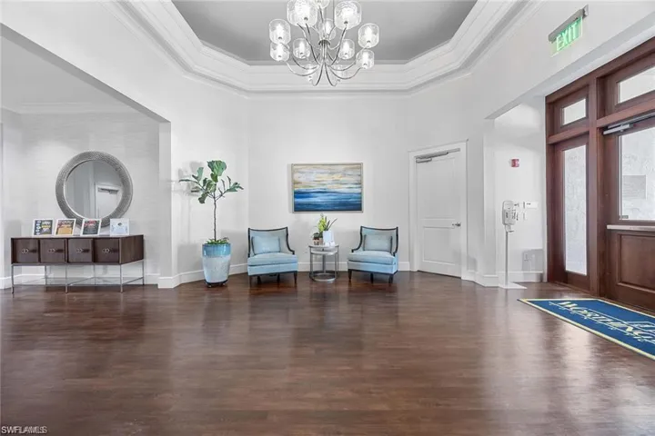 Foyer entrance with dark wood-style flooring, a chandelier, and crown molding