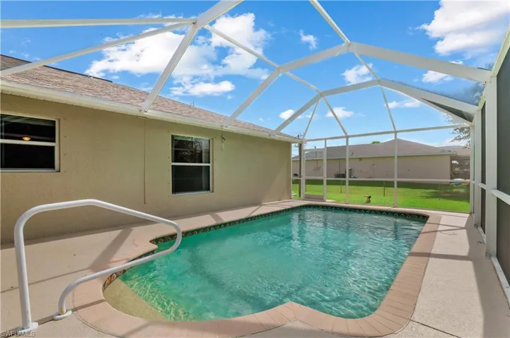 View of swimming pool featuring glass enclosure, a lawn, and a patio