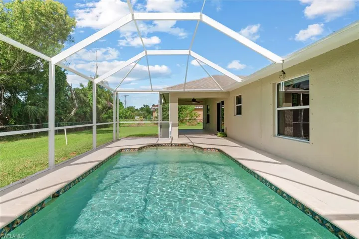 View of swimming pool featuring glass enclosure, a yard, and a patio area