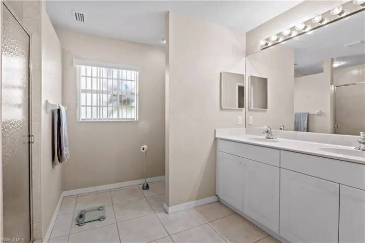 Bathroom with double vanity, an enclosed shower, and tile patterned flooring