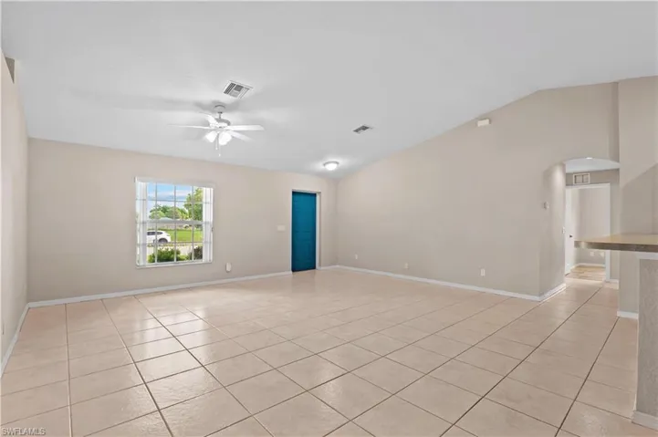 Tiled spare room with ceiling fan and vaulted ceiling