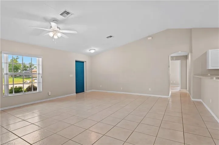 Tiled empty room with lofted ceiling and ceiling fan