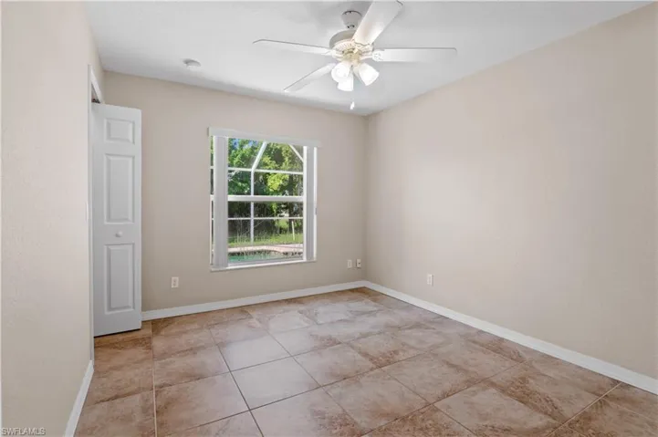 Empty room with light tile patterned floors and ceiling fan