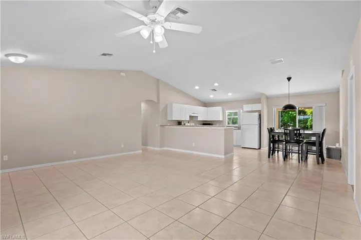 Unfurnished living room featuring ceiling fan, high vaulted ceiling, and light tile patterned floors