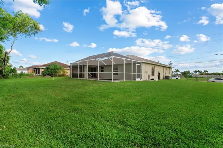 Back of property with a lanai and a lawn
