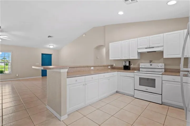 Kitchen featuring ceiling fan, white appliances, light tile patterned flooring, and lofted ceiling