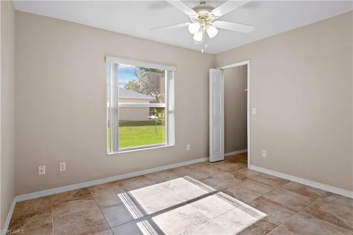 Tiled spare room featuring ceiling fan