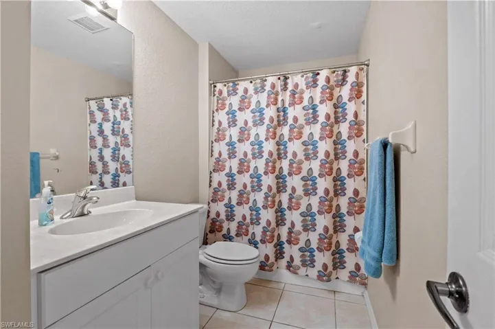 Bathroom featuring a textured ceiling, toilet, vanity, and tile patterned flooring