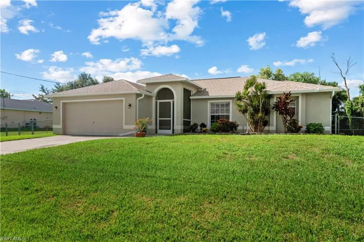 View of front of property with a garage and a front lawn