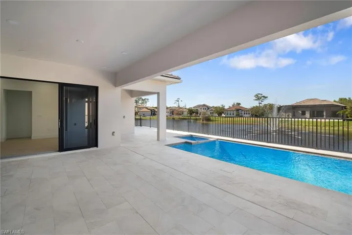 View of swimming pool with a water view, a patio, and an in ground hot tub
