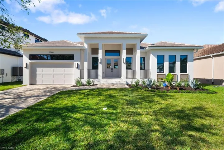 View of front of property featuring covered porch, a garage, and a front yard
