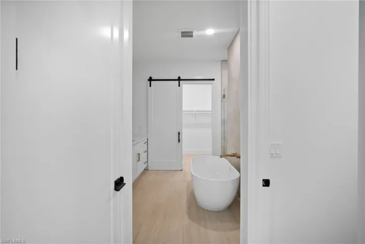 Bathroom with hardwood / wood-style flooring, vanity, and a tub to relax in