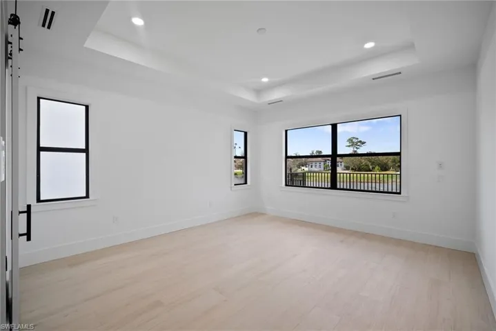 Unfurnished room with light wood-type flooring and a tray ceiling
