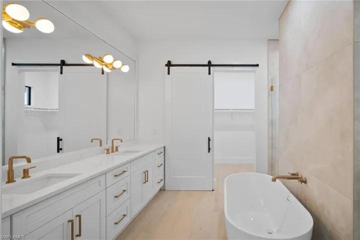 Bathroom featuring a bath, hardwood / wood-style floors, vanity, and tile walls