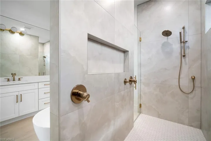 Bathroom featuring tiled shower and vanity