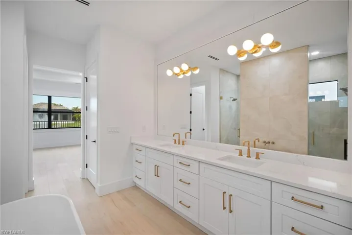 Bathroom featuring vanity, hardwood / wood-style floors, and plus walk in shower