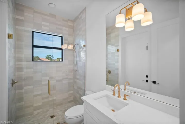 Bathroom featuring vanity, toilet, and an enclosed shower