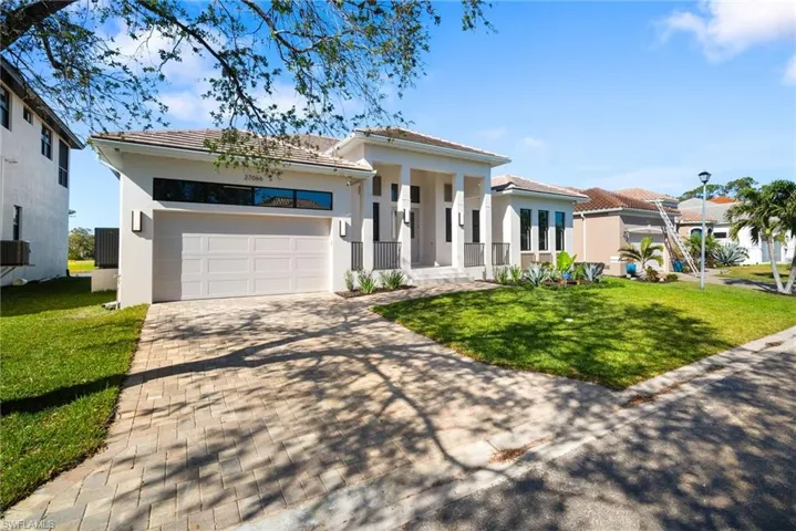 View of front of property featuring a porch, a garage, and a front yard