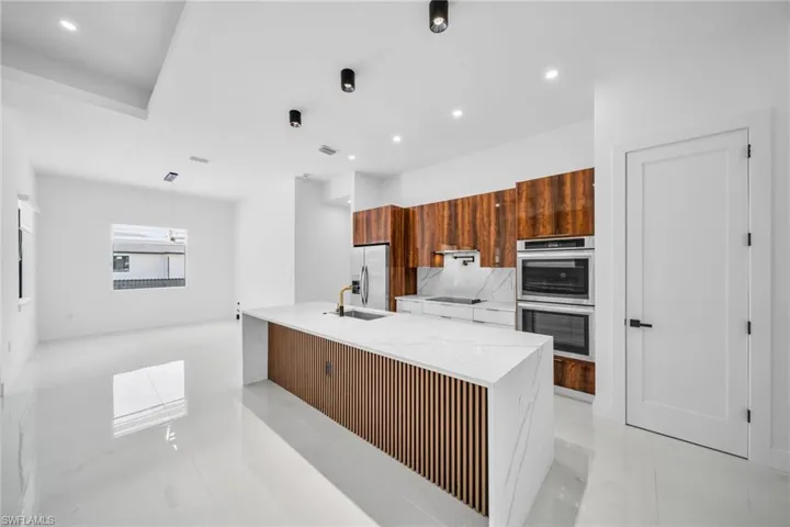Kitchen with brown cabinets, light stone countertops, modern cabinets, stainless steel appliances, and recessed lighting
