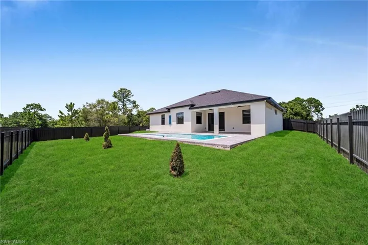 Rear view of property with a fenced backyard, stucco siding, and a patio area