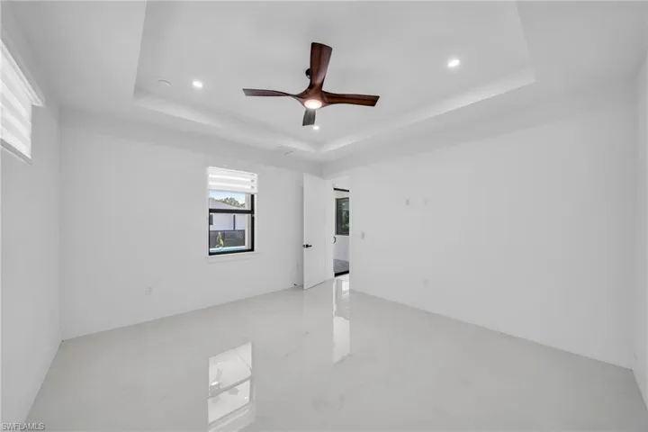 Empty room featuring a raised ceiling and ceiling fan
