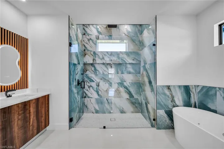 Full bathroom featuring vanity, a marble finish shower, a soaking tub, and tile patterned floors