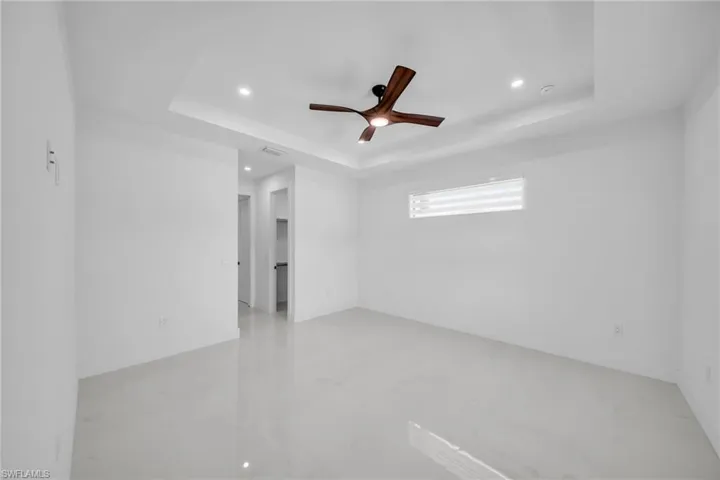 Unfurnished room with a ceiling fan, a raised ceiling, and recessed lighting