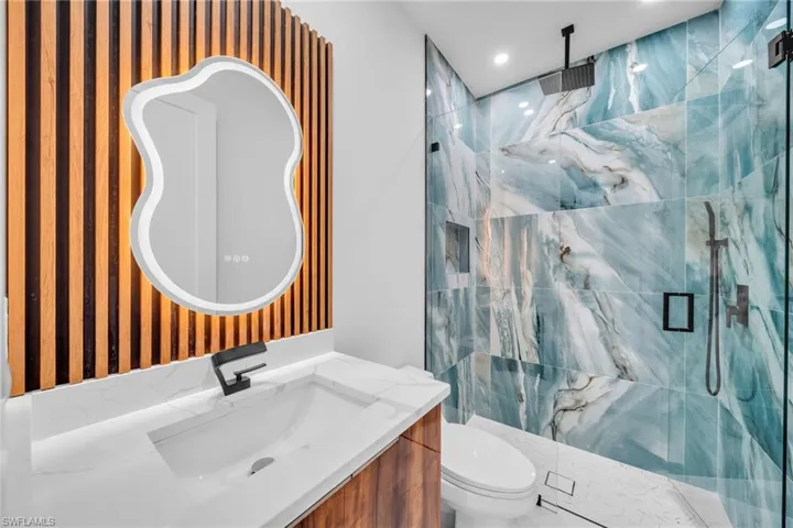Full bath with a marble finish shower, vanity, and recessed lighting