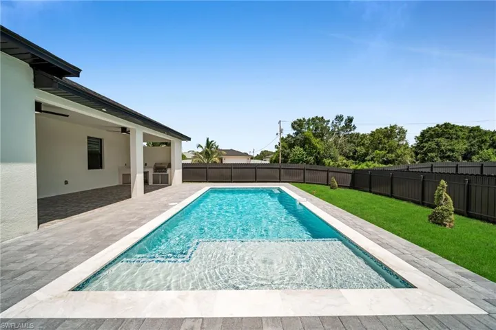 View of swimming pool featuring a patio area, a fenced backyard, and an outdoor kitchen
