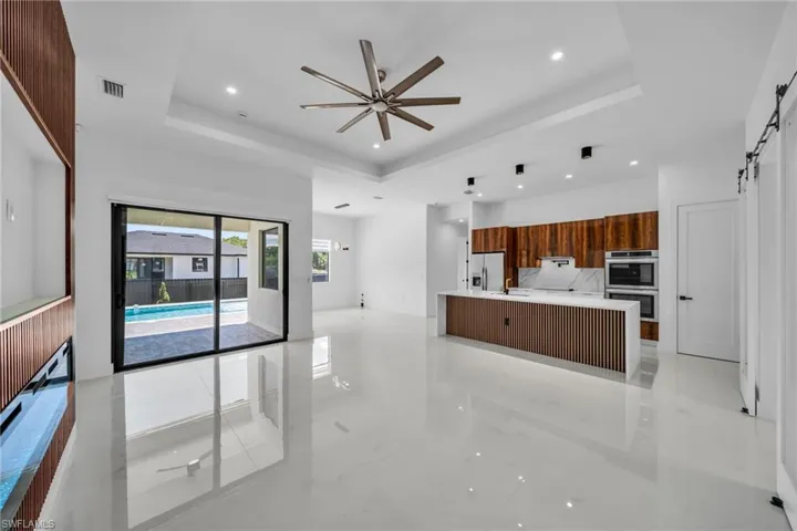 Kitchen with open floor plan, a tray ceiling, a barn door, modern cabinets, and recessed lighting