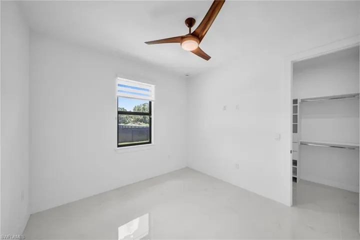 Unfurnished bedroom with a spacious closet and ceiling fan