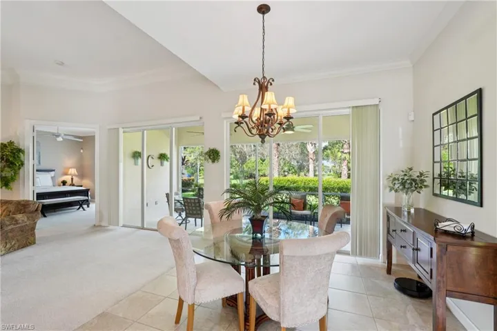 Dining area with ornamental molding, light colored carpet, light tile patterned floors, a chandelier, and a ceiling fan