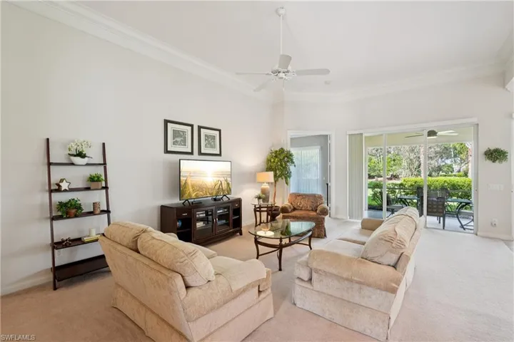 Living room featuring crown molding, light colored carpet, and a ceiling fan