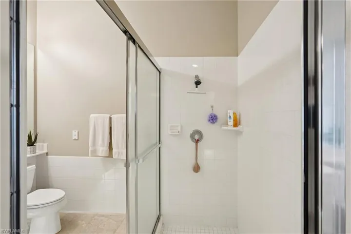 Full bath featuring a stall shower, tile walls, wainscoting, and light tile patterned floors
