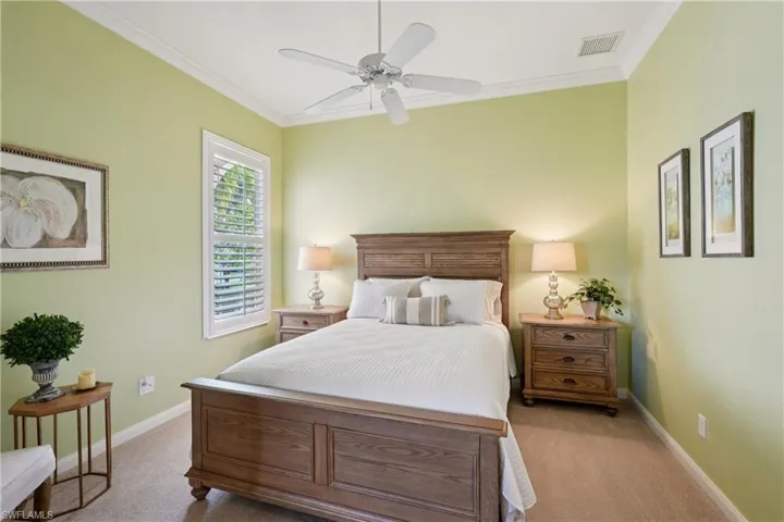 Bedroom featuring ornamental molding, light colored carpet, and ceiling fan